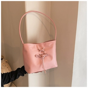Pink faux leather shoulder bag featuring decorative cross-lace and bow details