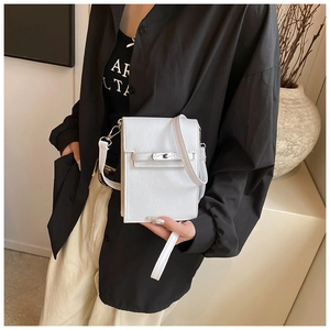 Vertical white crossbody phone bag with metal clasp shown on a model in a minimal setting