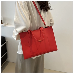 Close-up of red tote bag with JINPINPUU gold logo, outer pocket and adjustable strap