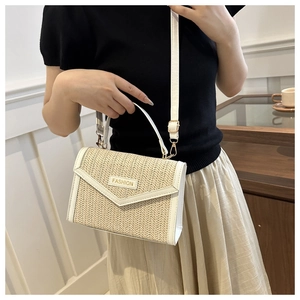 Détail du sac bandoulière en paille crème montrant la texture et la lanière