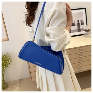 Detail of Klein blue leather shoulder bag featuring minimalist gold fashion lettering