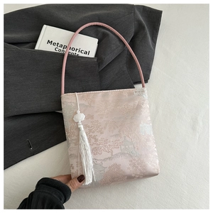 Detail einer rosa Jacquard-Beuteltasche mit traditioneller Stickerei und Quasten