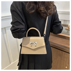 Detail of a beige bow-knot crossbody bag shown on a model for size and style reference