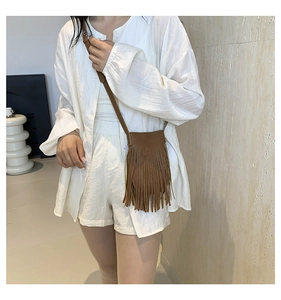 Close-up of a brown textured faux leather crossbody bag featuring long stylish tassels