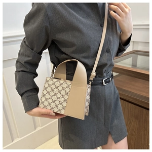 Seitenansicht einer beigefarbenen Damenhandtasche mit Blumenmuster und Goldringen