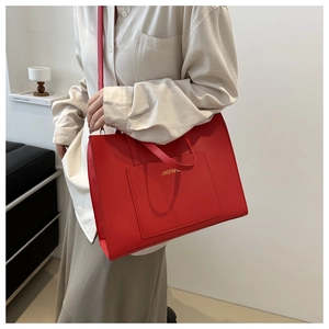 Macro detail of red faux leather tote bag showing gold JINGPINPIJU lettering and handle