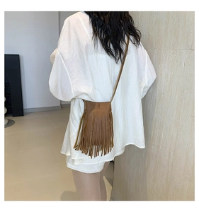 Detail of brown tassel crossbody phone bag with fringe texture and slim shoulder strap