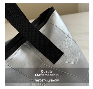Close-up of silver tote bag with lychee texture and black canvas handle stitching details