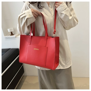 Detail of red leather tote bag with gold logo and shoulder strap for daily use
