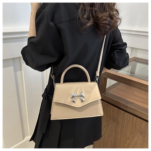 Chic cream leather crossbody bag featuring a 3D silver metal bow and flap design