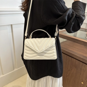 White quilted shoulder bag with V-shaped texture and matching leather strap in daily use