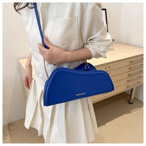 Detail view of Klein blue irregular wavy bag with gold lettering and slim shoulder strap