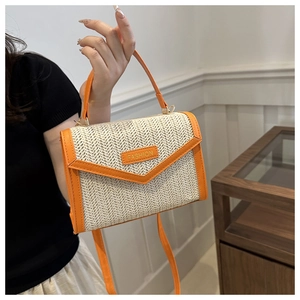 Détail du sac en paille tressée avec bordure orange et badge de mode en métal