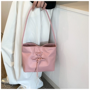 Detail of pink faux leather tote bag with elegant cross-lacing and bowknot decoration