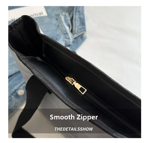 Close-up of smooth metal zipper and quilted texture on the black shoulder tote bag