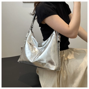 Détail du sac argenté métallisé avec logo MUDO embossé et bandoulière en chaîne fine