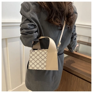 Schicke Handtasche aus beigem und braunem Patchwork, von einem Model im Raum getragen