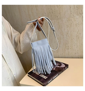 Detail of light blue fringe crossbody bag with litchi grain texture held by hand