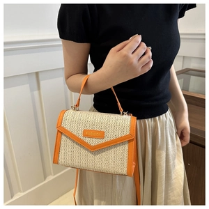 Close-up of woven straw handbag with orange leather trim and FASHION label detail