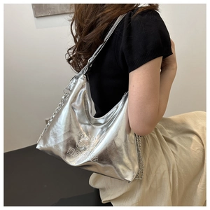 Detail view of the silver metallic shoulder bag showing embossed lettering and chain strap