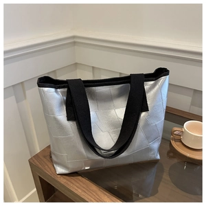 Detailed view of silver metallic geometric tote bag on a modern glass table