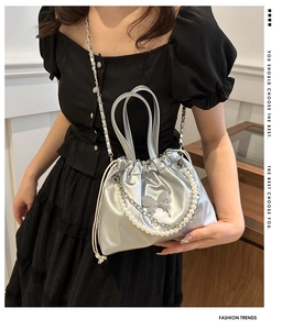 Detail of silver bucket bag featuring pearl handle and metallic butterfly ornament