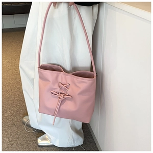Detailed view of pink shoulder bag with decorative cross lacing and sweet bow accent