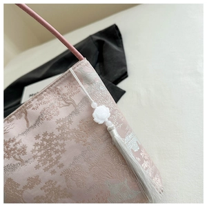 Détail du sac seau en soie rose avec broderie traditionnelle et gland décoratif