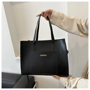Detail shot of black tote bag with front pocket and gold logo for daily commute