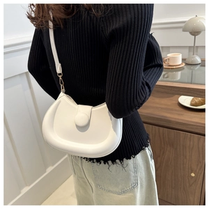 Detail of white half-moon shoulder bag with round buckle and adjustable leather strap