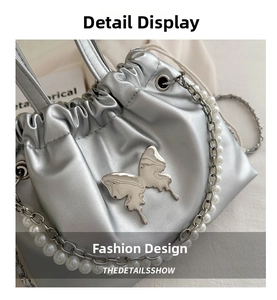 Close-up of silver drawstring bucket bag with butterfly metal accent and pearl handle