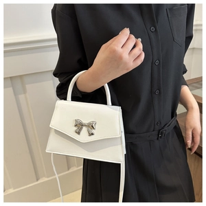 Close-up of white crossbody bag featuring a silver bow-knot metal buckle and smooth finish