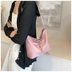 Detailed view of pink shoulder bag with bow drawstring and soft leather-like finish