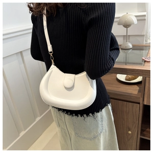 Detail of white crescent shoulder bag with minimalist circular buckle and gold hardware