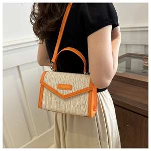 Detail of straw woven bag featuring vibrant orange leather trim and fashion plaque detail