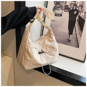 Detail view of beige nylon crossbody bag with drawstring ruching and black zipper