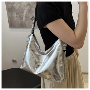 Détail du sac à bandoulière argenté avec lettres embossées et texture de la chaîne