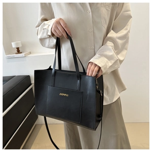 Close-up of black leather tote bag featuring a front pocket and elegant gold logo lettering