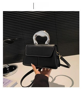 Détail du sac bandoulière noir avec une poignée métallique argentée de forme atypique