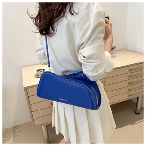 Detail of royal blue leather shoulder bag with gold lettering shown in a home setting