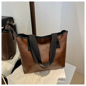 Close-up of brown PU leather tote bag featuring geometric stitching and wide canvas strap