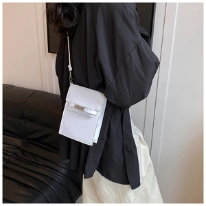 Detailed view of a white minimalist crossbody bag with silver twist lock and strap detail