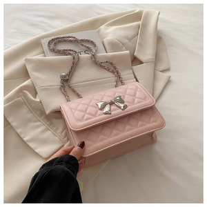 Close-up of pink quilted crossbody bag with silver bow clasp and chain strap detail