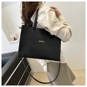 Detailed view of a black tote bag showing smooth faux leather texture and front pocket