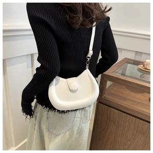 Detail of white PU leather crescent bag with golden hardware on a shoulder strap