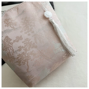 Détail du sac en brocart rose brodé avec pompons argentés et pendentif lotus