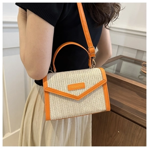 Detail of woven straw handbag with orange trim and metal hardware in daily lifestyle scene