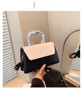 Détail du sac contrasté avec poignée en métal fluide argenté et rabat en cuir blanc