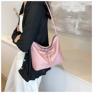 Detail of soft pink PU hobo bag featuring decorative drawstring bow and textured leather