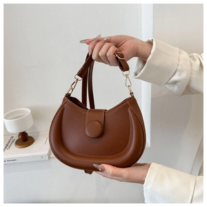 Detailed close-up of brown matte leather saddle bag with gold hardware and flap closure